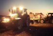 Agrárna ekonomika, agrárna politika - dva traktory na poli nakladajú balíky slamy na vlečku za traktor