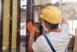 Male builder repairing door in building under construction